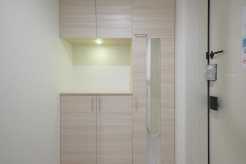 a kitchen with wooden cabinets and a white wall at Z LAND Enoshima in Fujisawa