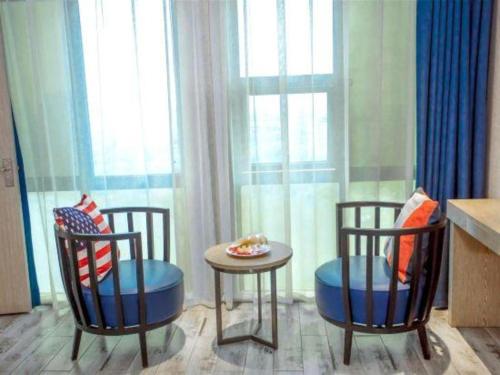 two chairs and a table in front of a window at Kyriad Marvelous Hotel Xiangyin Bus Station in Xiangyin