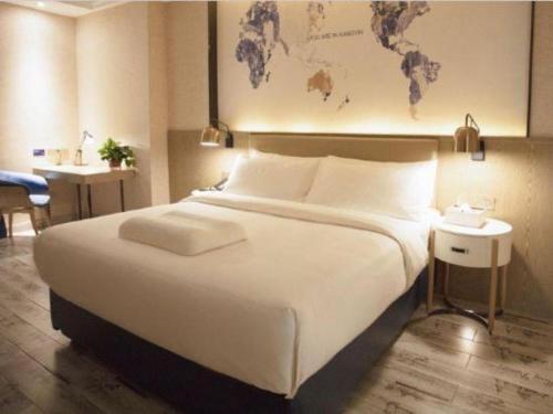 a bedroom with a large white bed with a map on the wall at Kyriad Marvelous Hotel Xiangyin Bus Station in Xiangyin