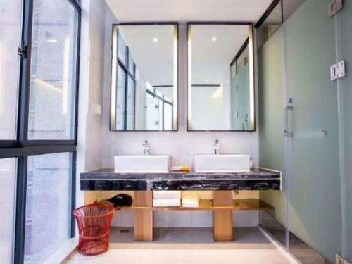 a bathroom with two sinks and two mirrors at Kyriad Marvelous Hotel Xiangyin Bus Station in Xiangyin