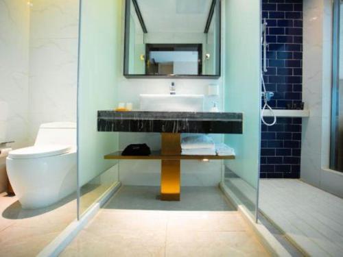 a bathroom with a sink and a toilet and a mirror at Kyriad Marvelous Hotel Xiangyin Bus Station in Xiangyin