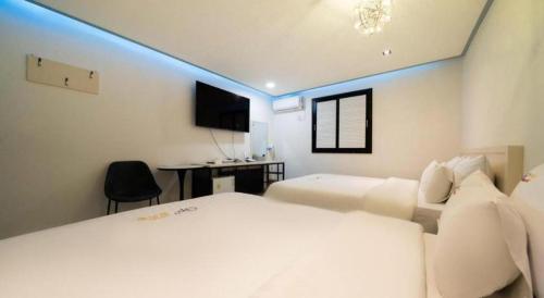 a bedroom with two beds and a desk and a television at Chuncheon World Hotel in Chuncheon