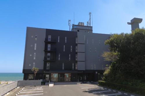a black building with the ocean in the background at Shiosai Resort Kamogawa in Kamogawa