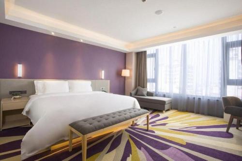 a bedroom with a large bed and a purple wall at Lavande Hotel·Dongxing Port in Fangcheng