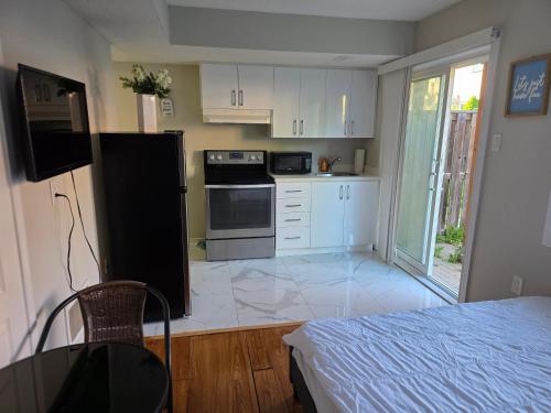 een keuken met witte kasten en een zwarte koelkast bij Beautiful Studio with Patio in Mississauga in Mississauga