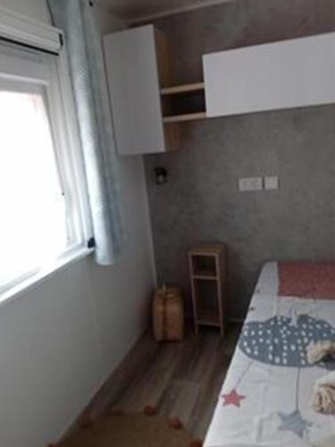 une petite chambre avec un lit et une fenêtre dans l'établissement CAMPING Les EMBRUNS - 4 ETOILES, à Lège-Cap-Ferret