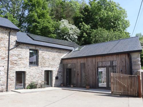 an old brick building with a black roof at 3 Caddaford Barns in Buckfastleigh