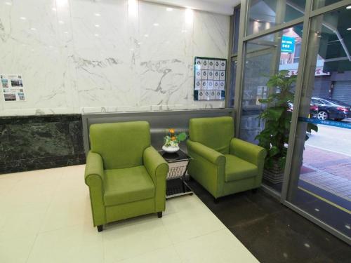 two green chairs sitting in a waiting room at West Hotel in Hong Kong