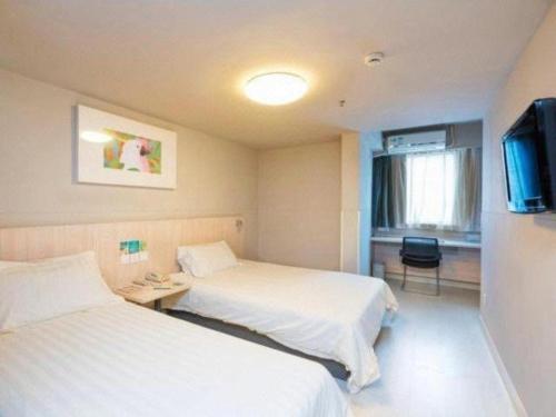 a hotel room with two beds and a flat screen tv at Jinjiang Inn Wuhu Fangte Tech Museum Metro Station in Wuhu