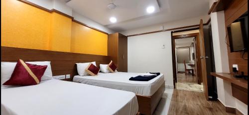a hotel room with two beds and a television at Alfouz Guest House in Chennai