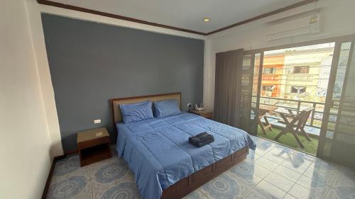 a bedroom with a bed with a blue comforter and a balcony at Chalong Paradise Guesthouse in Ban Bang Chak