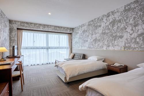 a hotel room with two beds and a window at Shiosai Resort Kamogawa in Kamogawa