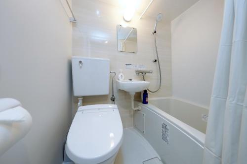 a white bathroom with a toilet and a sink at Flat K Plum Umegaoka in Tokyo