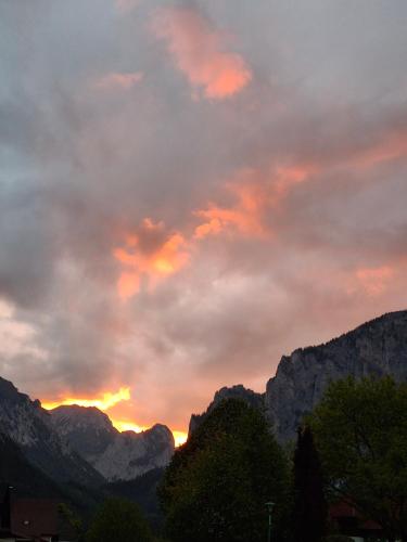 a sunset in the mountains with trees and clouds at Haus Bergblick am Grünen See in Oberort