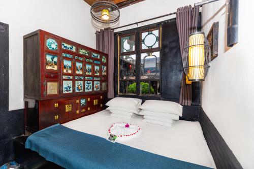 a bedroom with a bed with white sheets and a window at Elsewhere Hotel The former residence of the draft bank in Pingyao