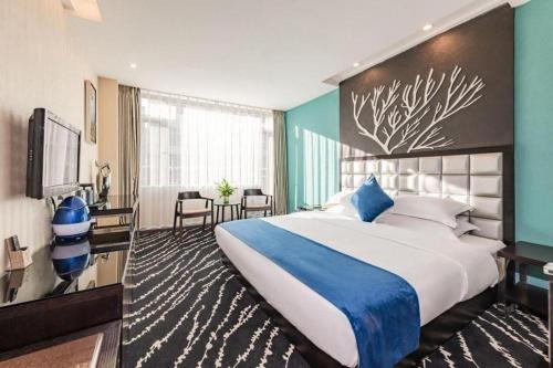 a hotel room with a large bed with a blue and white bedspread at Kunming Long Way Hotel in Kunming