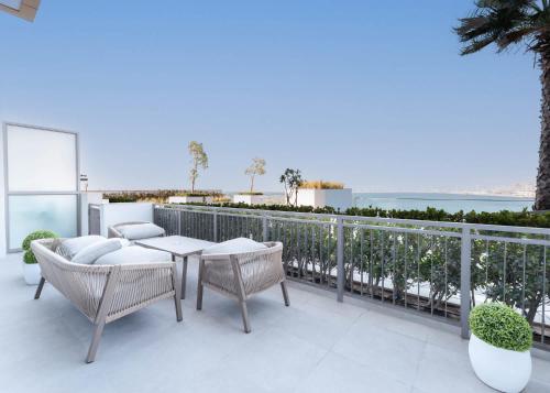 a patio with a table and chairs on a balcony at Free housekeeping visits during your stay - StayShort - Stunning Sea View Escape at Anwa by Omniyat in Dubai