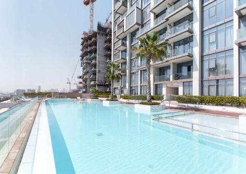 a large swimming pool in front of a building at Free housekeeping visits during your stay - StayShort - Stunning Sea View Escape at Anwa by Omniyat in Dubai