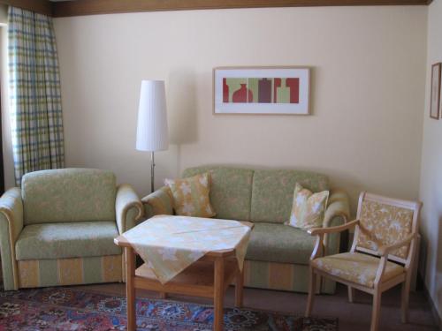 a living room with a couch and a table and a chair at Landhotel Maiergschwendt inkl Chiemgaukarte in Ruhpolding
