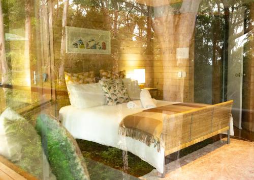 une chambre avec un lit et une paroi vitrée dans l'établissement Bombah Point Eco Cottages, à Bulahdelah