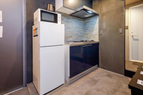 a kitchen with a white refrigerator and a sink at Flat K Plum Umegaoka in Tokyo