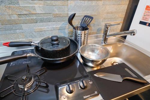 a frying pan on top of a stove next to a sink at Flat K Plum Umegaoka in Tokyo
