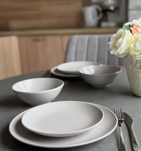 a table with white plates and bowls and a fork at Poilsis Kunigiškiuose in Palanga