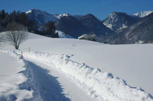a snow covered road with mountains in the background at Landhotel Maiergschwendt inkl Chiemgaukarte in Ruhpolding