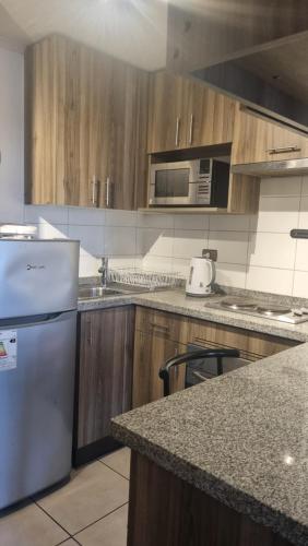 a kitchen with wooden cabinets and a white refrigerator at Departamento Centro de La Florida in Santiago