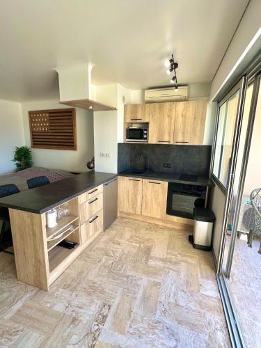 une cuisine avec des armoires en bois et un comptoir noir dans l'établissement Beau studio residences Marina parking privé, à Mandelieu-la-Napoule