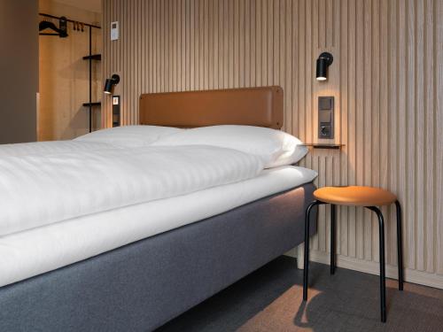 a bed in a room with a stool next to it at Zleep Hotel Frankfurt Airport Kelsterbach in Kelsterbach