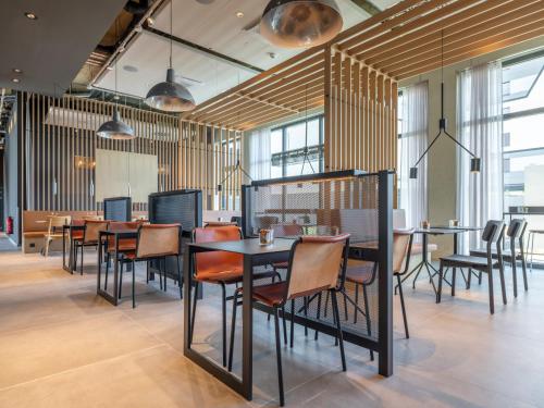 a dining room with tables and chairs and windows at Zleep Hotel Frankfurt Airport Kelsterbach in Kelsterbach