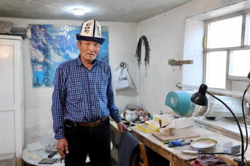 a man wearing a hat standing in a kitchen at guest House Nur Emgekchil in Emgekchil