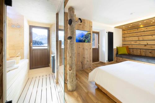a bedroom with a large bed and a bathroom at Hotel Miralago in Misurina