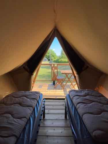 two beds in a tent with a view of a patio at Camping les Marguerites in Gamaches