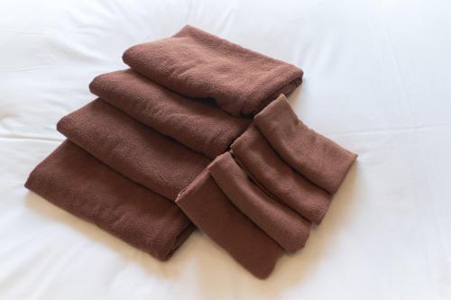 a pile of brown towels sitting on a bed at Cure Azumabashi in Tokyo