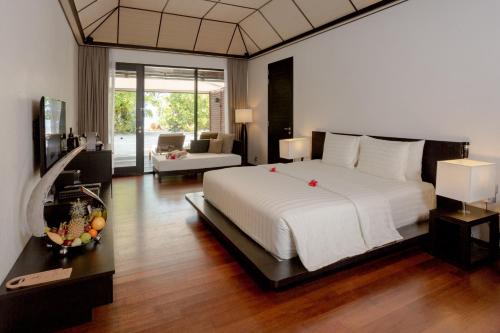 a bedroom with a large white bed and a living room at Lily Beach Resort and Spa - All Inclusive in Dhangethi