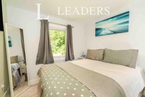 a bedroom with a bed and a window with the words leaders at Adorable Self Contained detached annexe in Holmwood