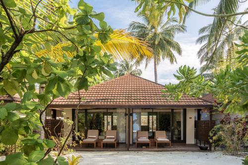 a house with a porch with chairs and trees at Lily Beach Resort and Spa - All Inclusive in Dhangethi