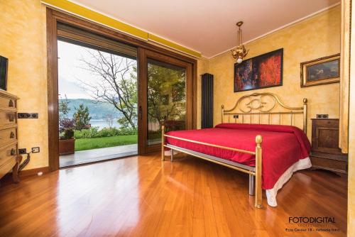 een slaapkamer met een rood bed en een groot raam bij B&B Renalù in Verbania