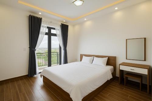 a bedroom with a white bed and a window at Villa Thanh Thanh in Da Lat