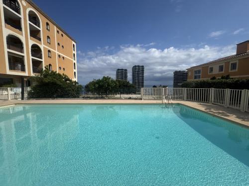 une grande piscine bleue à côté d'un immeuble dans l'établissement STUDIO BEAUSOLEILMONACO TERRASSE VUE MER Clim et Accès Piscine, à Beausoleil