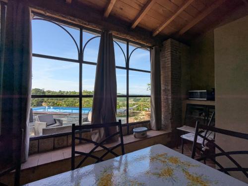 a dining room with a large window with a view of a pool at Podere Rinascidentro in Asciano