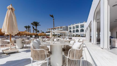 a restaurant with white tables and chairs and a umbrella at Sunrise Remal Beach Resort in Sharm El Sheikh