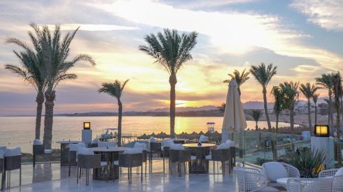 a restaurant with tables and chairs and palm trees at Sunrise Remal Beach Resort in Sharm El Sheikh