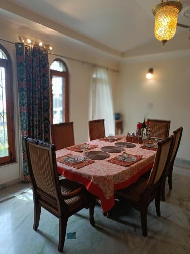 a dining room table with a red table cloth and chairs at the Kutumb- Where the Himalayas come alive! in Pālampur