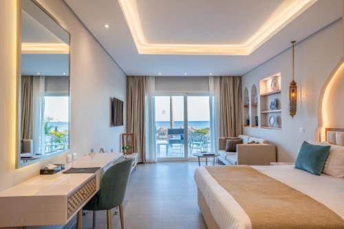 a hotel room with a large bed and a desk and a room at Sunrise Remal Beach Resort in Sharm El Sheikh