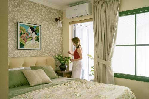 a woman standing in a bedroom looking out the window at Leng - Duplex Onsen Swanlake Ecopark in Kim Quan