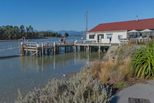 a dock with a building next to a body of water at Mana Nalu - Mapua Holiday Home in Mapua