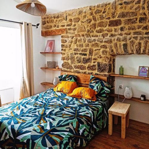 une chambre avec un lit et un mur en pierre dans l'établissement Charmante maison de campagne, à Saint-Victor